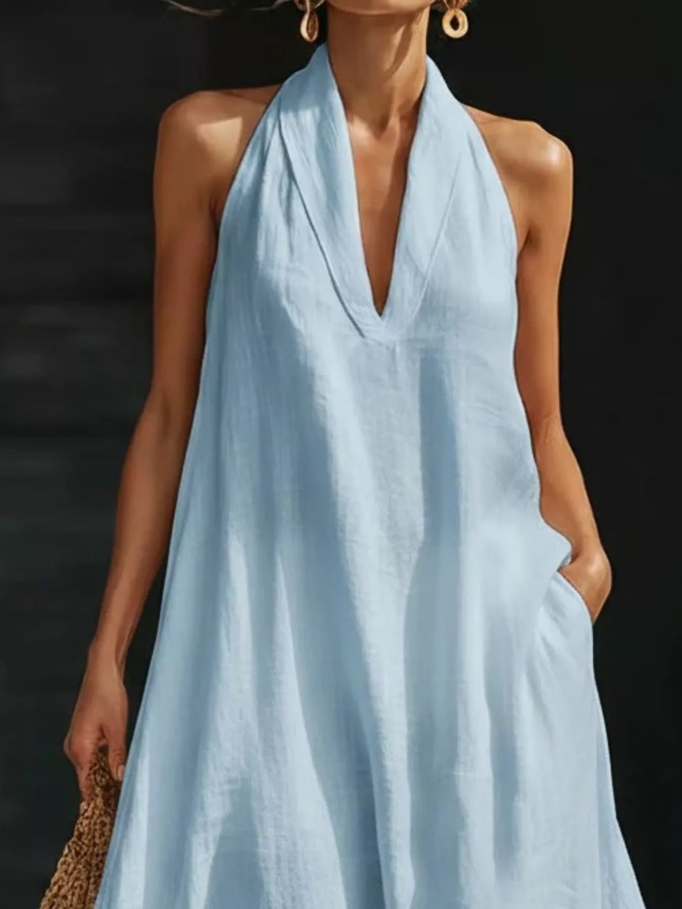 Woman wearing a light blue halter neck dress against a dark background