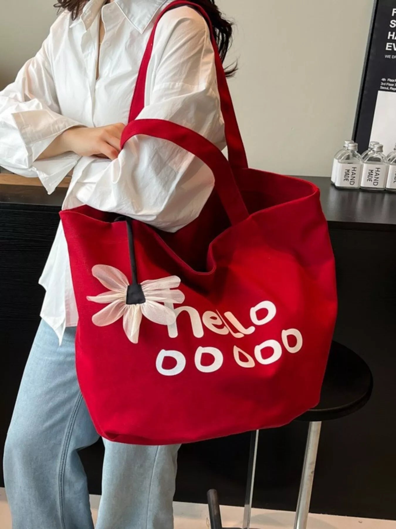 Person holding a red tote bag with floral design and 'hello dodo' text.