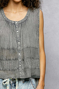 Person wearing a sleeveless denim top with a gray background