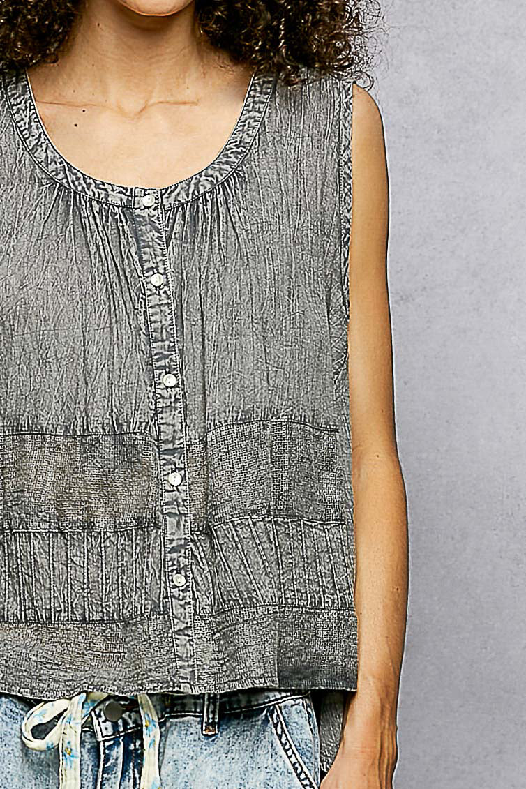 Person wearing a sleeveless denim top with a gray background