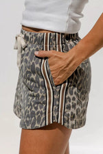 Leopard print shorts with striped details worn by a person on a plain background