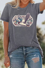 Person wearing a gray t-shirt with a duck graphic design outdoors