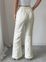 Person wearing textured white pants against a neutral background