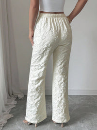 Person wearing textured white pants against a neutral background