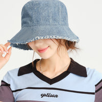 Person wearing a denim bucket hat with a plain background