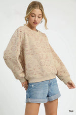 Woman wearing a beige patterned sweater and denim shorts on a white background