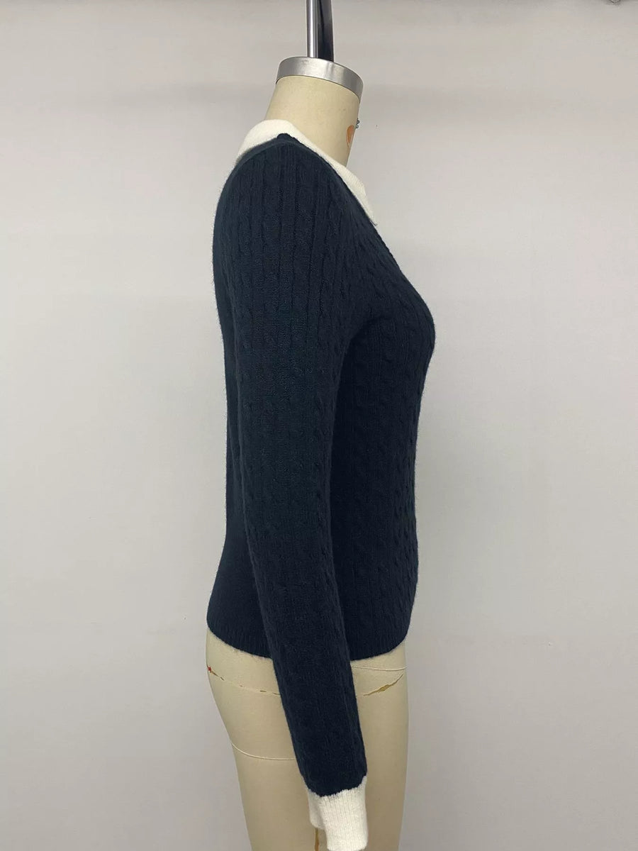 A dark navy blue cable-knit sweater with a contrasting white collar, cuffs, and hem, displayed on a beige mannequin torso against a plain light gray background.