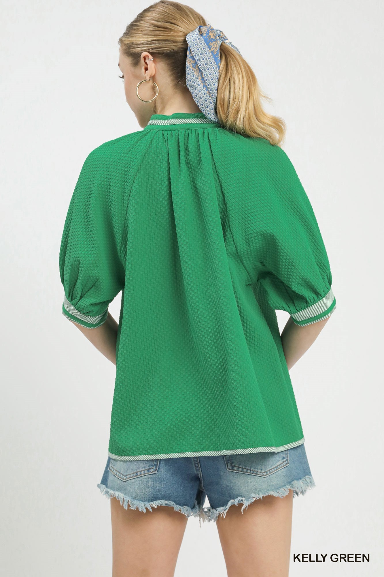 Woman wearing a green blouse with puffed sleeves on a white background
