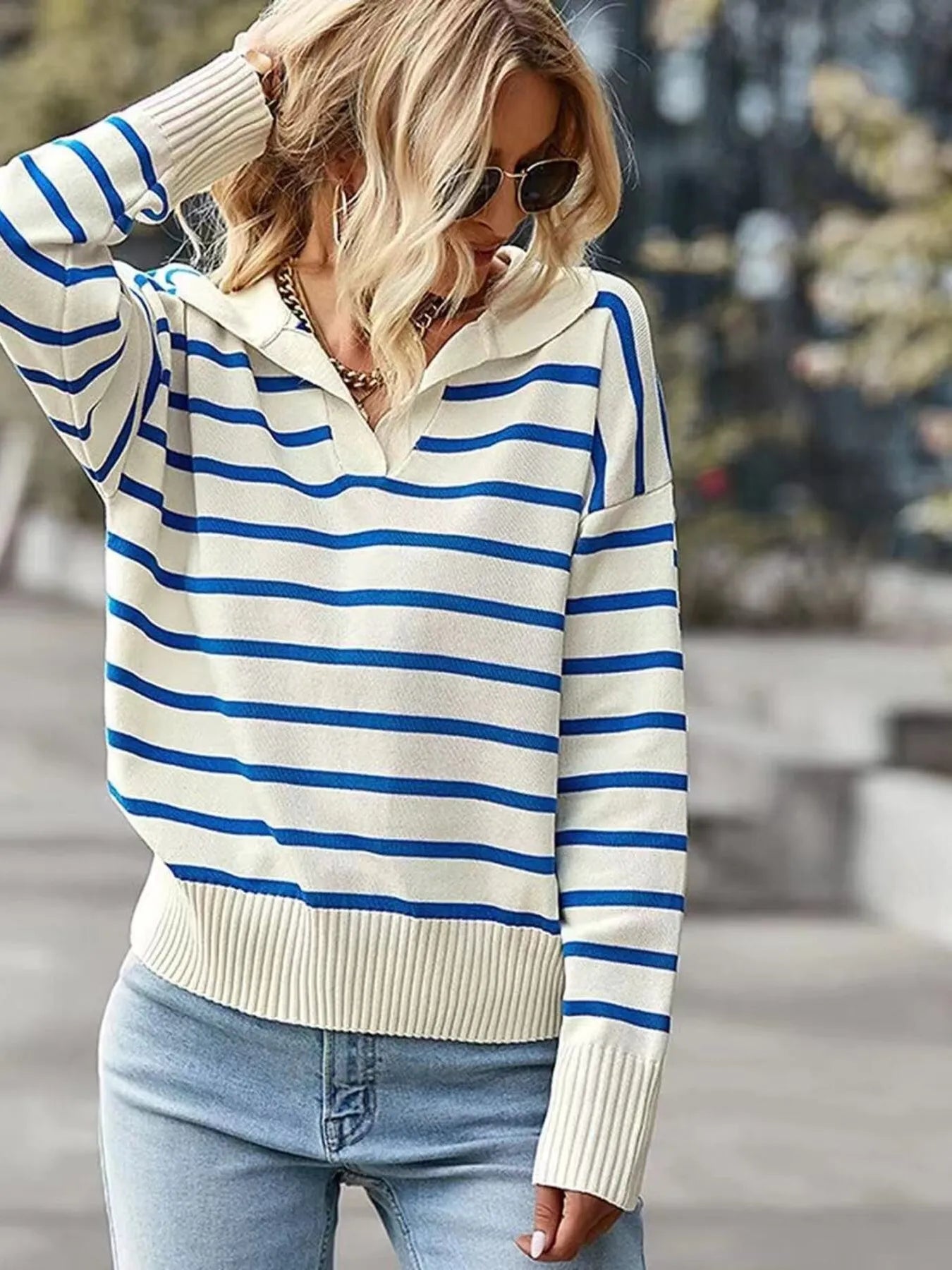 Woman wearing a blue and white striped sweater with a blurred outdoor background