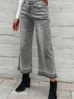 Person wearing gray wide-leg jeans against a stone wall.