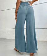Teal wide-leg pants worn by a person on a light gray background