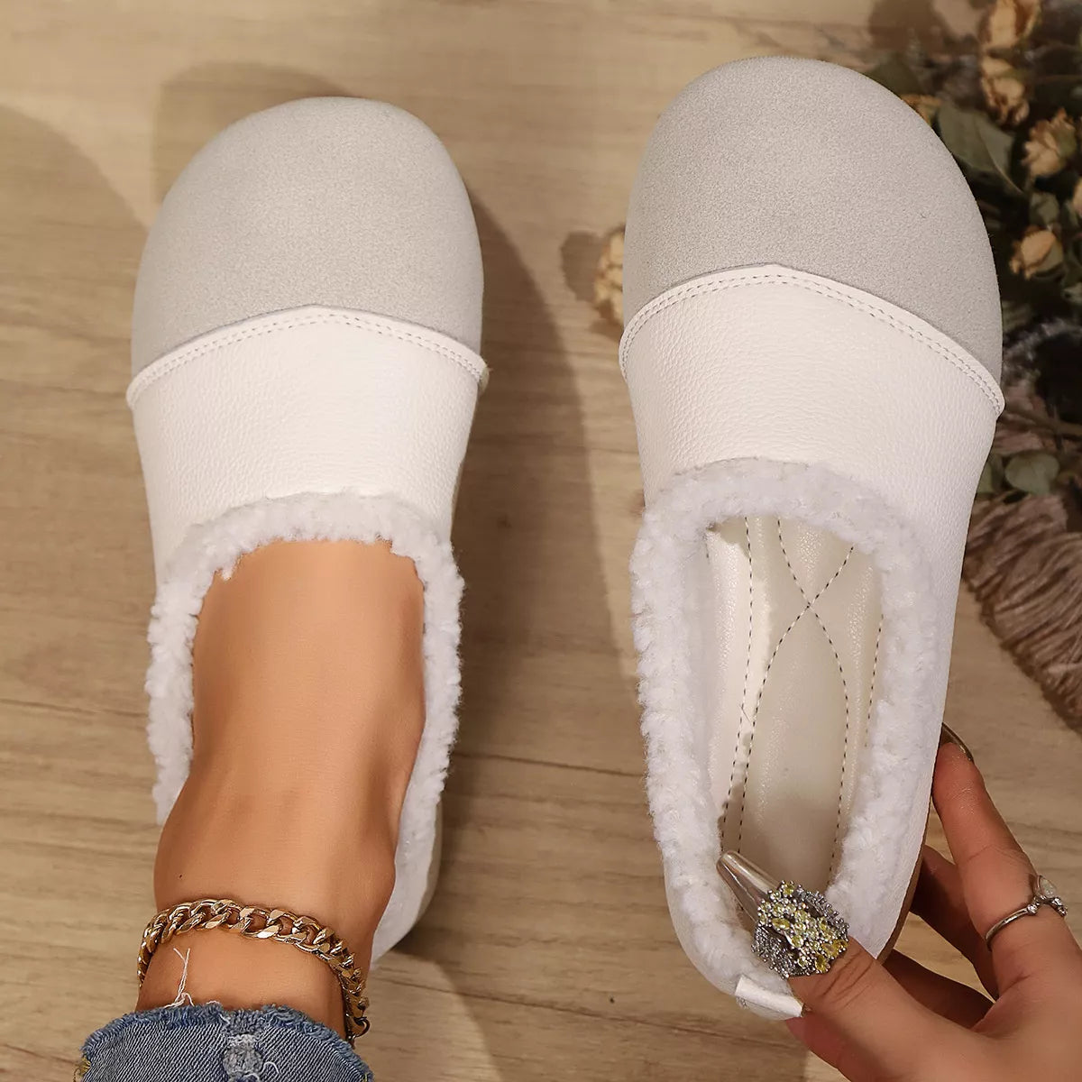 White and gray slippers being worn on a wooden floor.