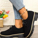 Black shoes with thick soles worn by a person, with a decorative background.
