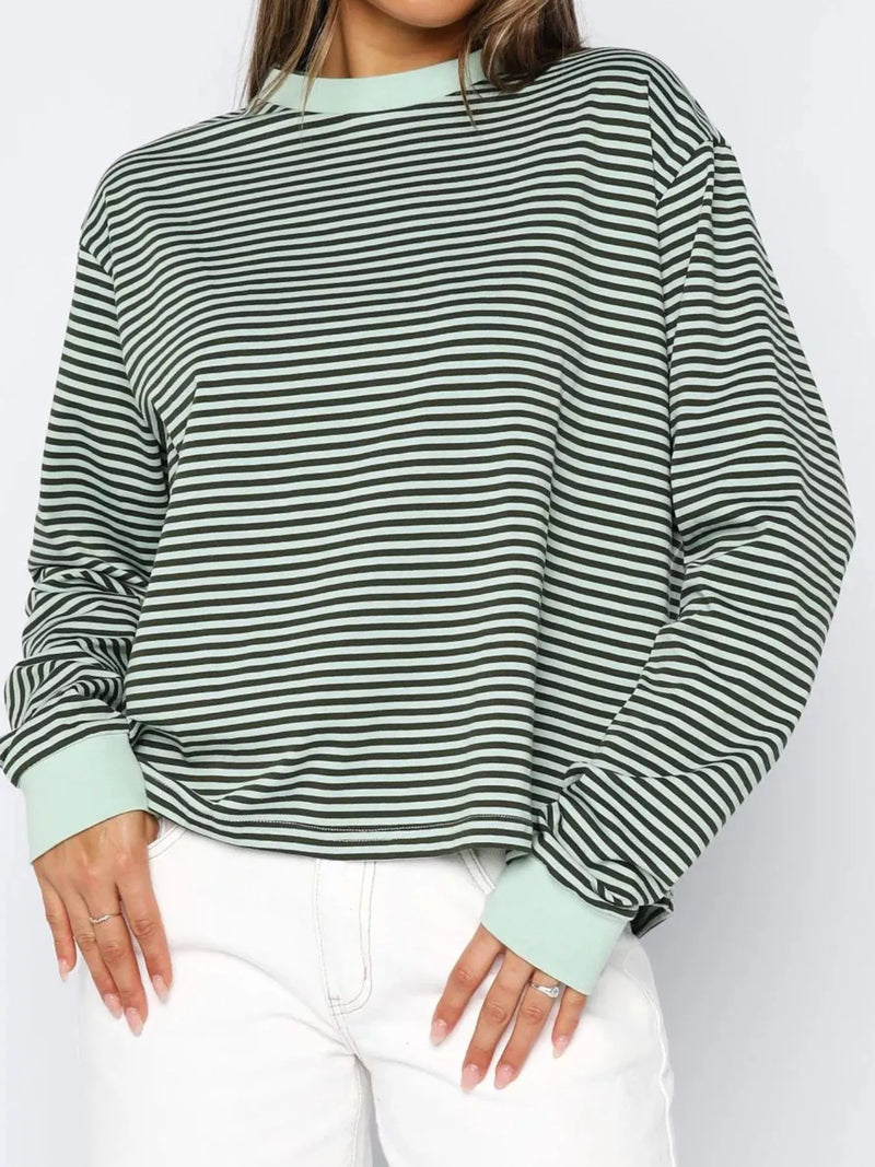 Person wearing a green and black striped sweater with light green cuffs and collar on a white background