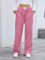 Red and white checkered pants worn by a person on a gray pavement.