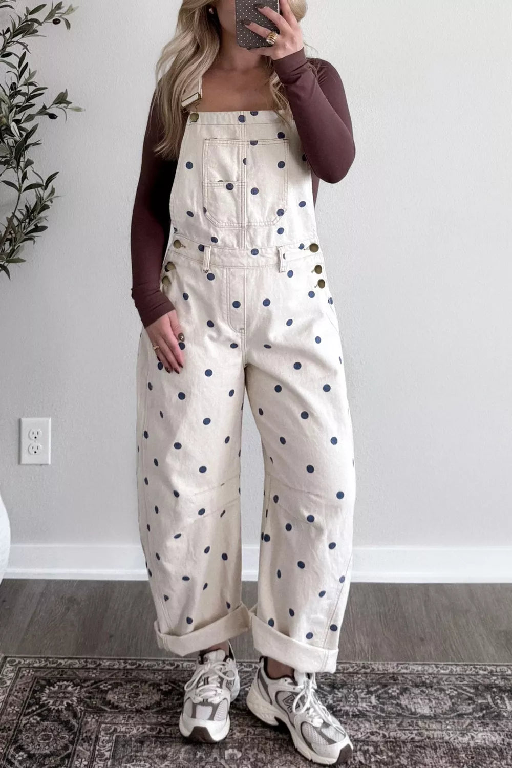Person wearing a white jumpsuit with black polka dots, standing indoors.