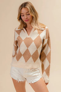 Woman wearing a beige and brown argyle sweater with white shorts on a beige background