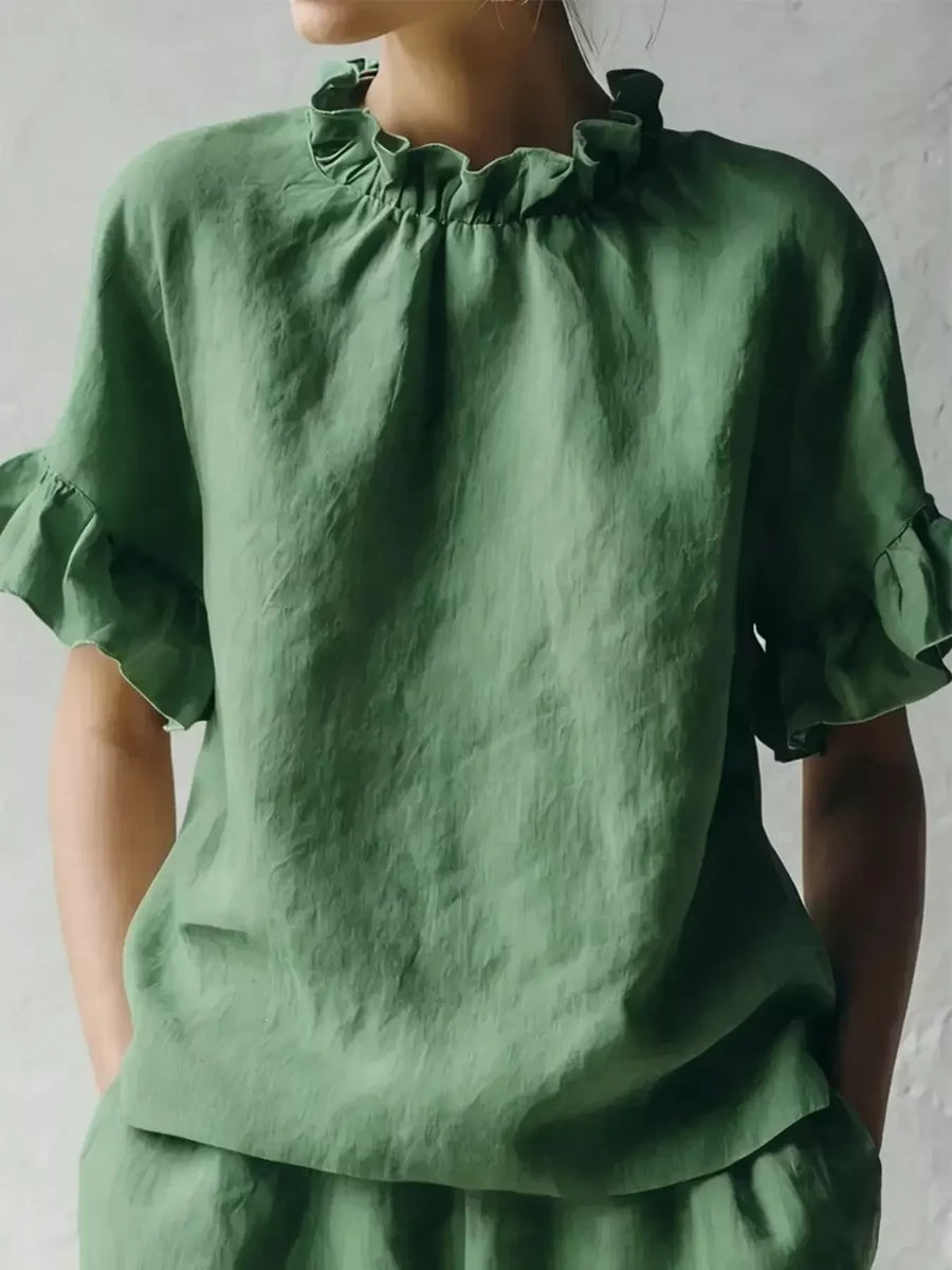 Green linen top worn by a person against a plain background