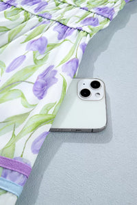 Smartphone on a textured surface with a floral dress in the background