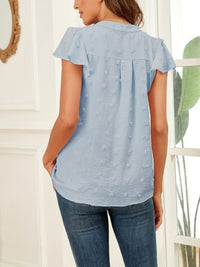 Woman wearing a light blue blouse with short sleeves and a white background