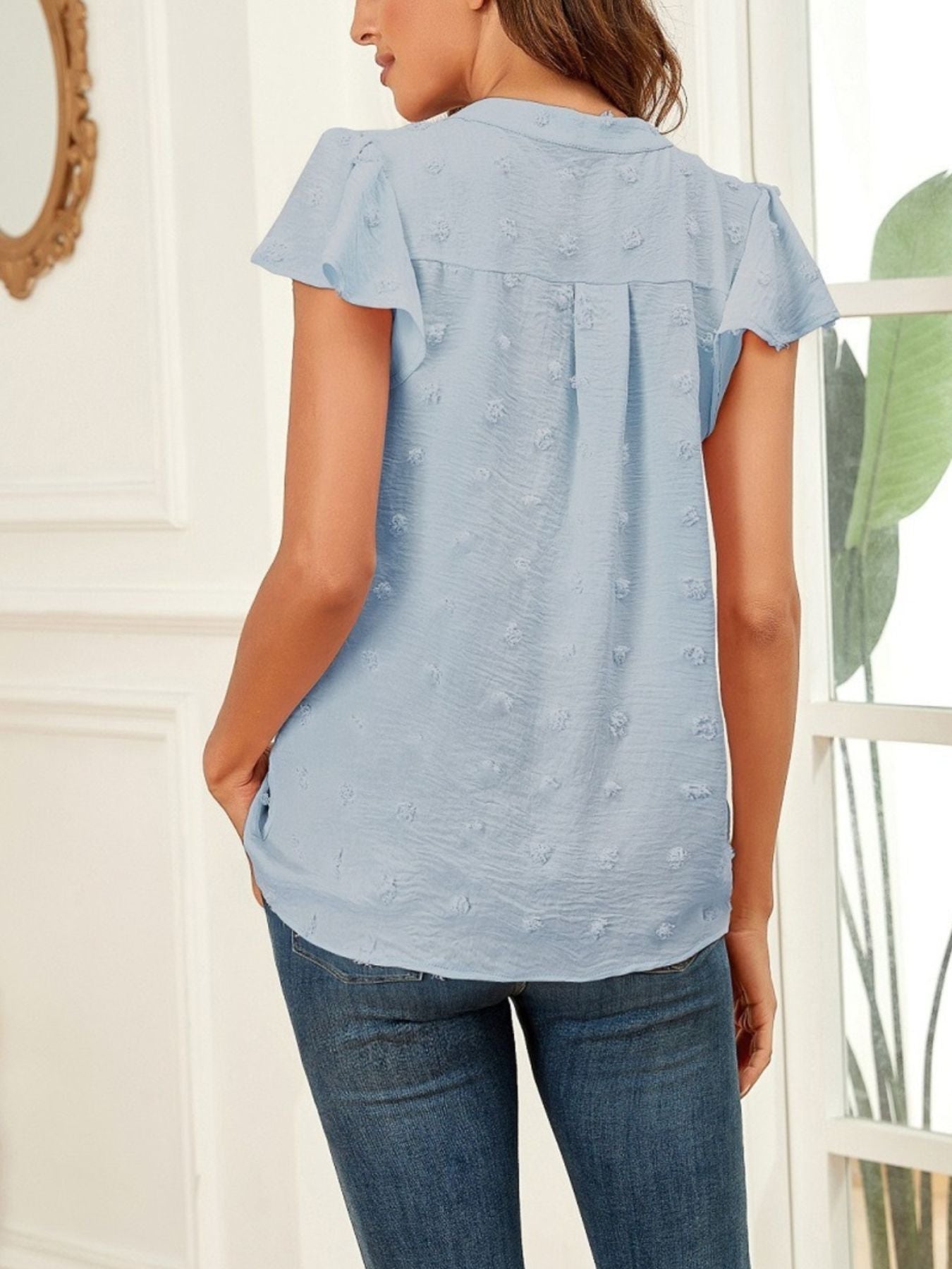 Woman wearing a light blue blouse with short sleeves and a white background