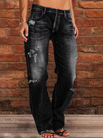 Person wearing distressed black jeans against a brick wall.