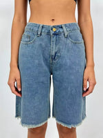 Blue denim shorts worn by a person on a plain background