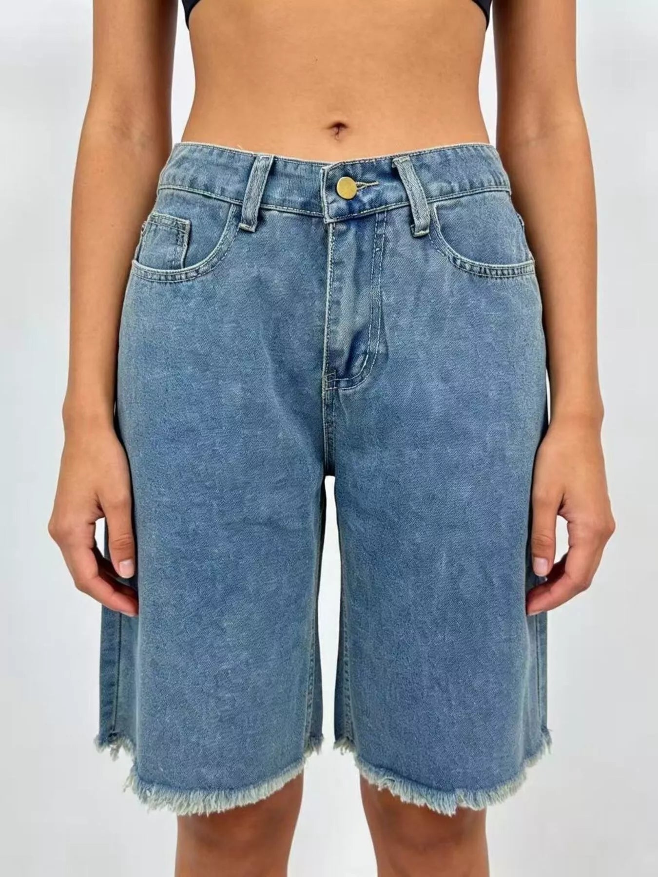 Blue denim shorts worn by a person on a plain background