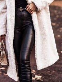 Person wearing a white coat, black leather pants, and a Gucci belt.