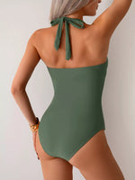 Green one-piece swimsuit with a tie back detail on a plain background