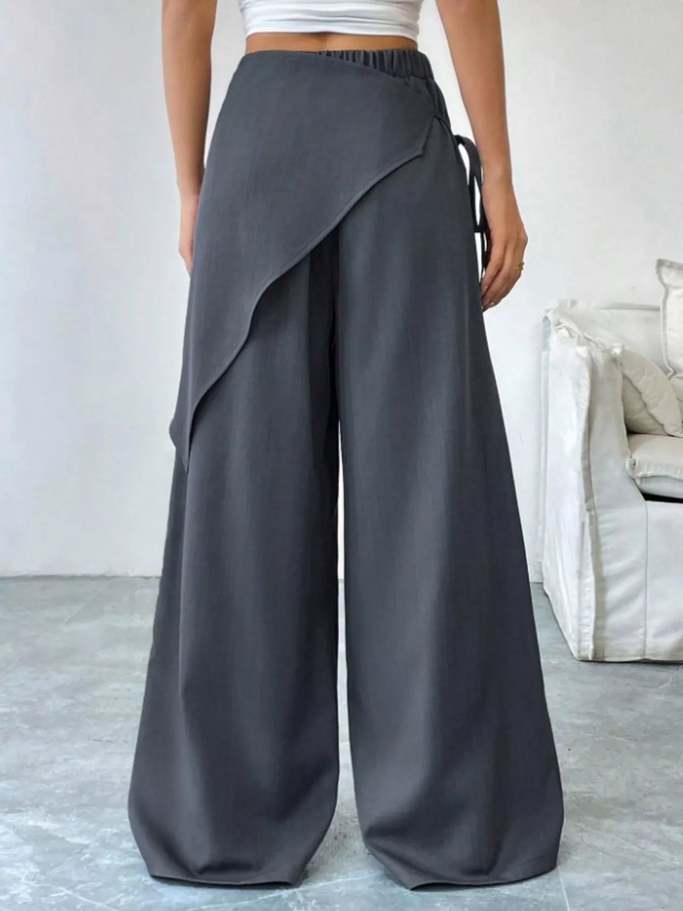 Person wearing gray wide-leg pants in a minimal indoor setting
