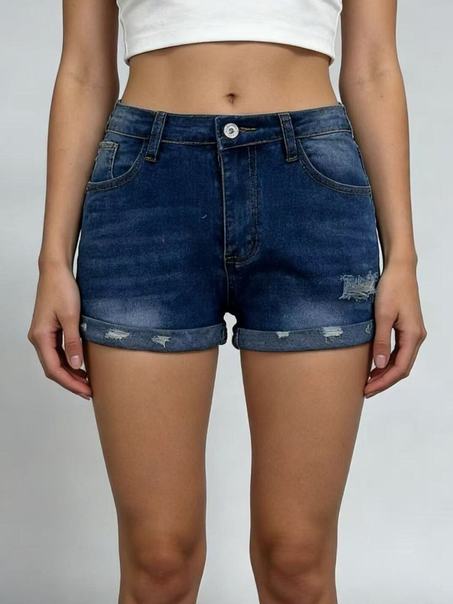 Person wearing blue denim shorts on a plain background