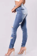 Ripped blue jeans worn by a person on a light gray background