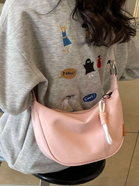 Person wearing a gray sweatshirt with colorful designs, holding a pink bag.