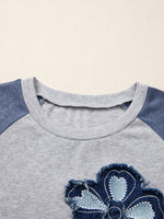 Close-up of a gray and blue children's shirt with a floral design on a beige background