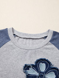 Close-up of a gray and blue children's shirt with a floral design on a beige background