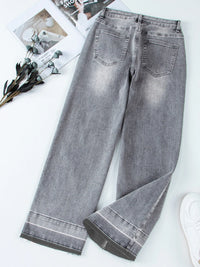 Gray jeans on a white surface with a magazine and flowers in the background