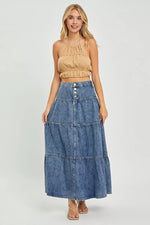 Woman wearing a beige top and denim skirt on a white background