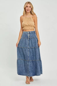 Woman wearing a beige top and denim skirt on a white background