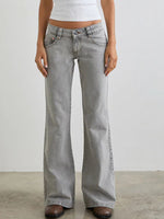 Person wearing light gray flared jeans on a plain background