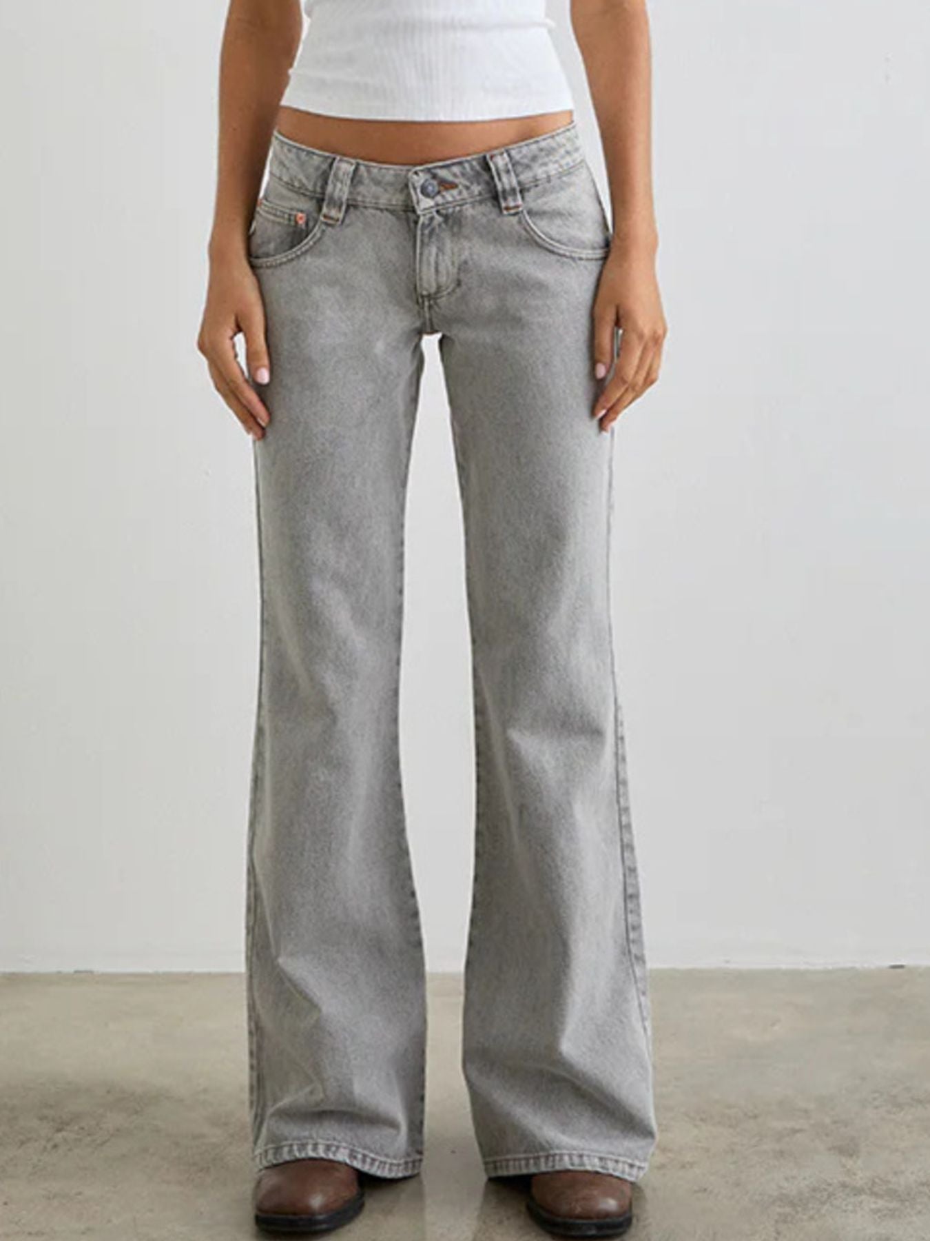 Person wearing light gray flared jeans on a plain background