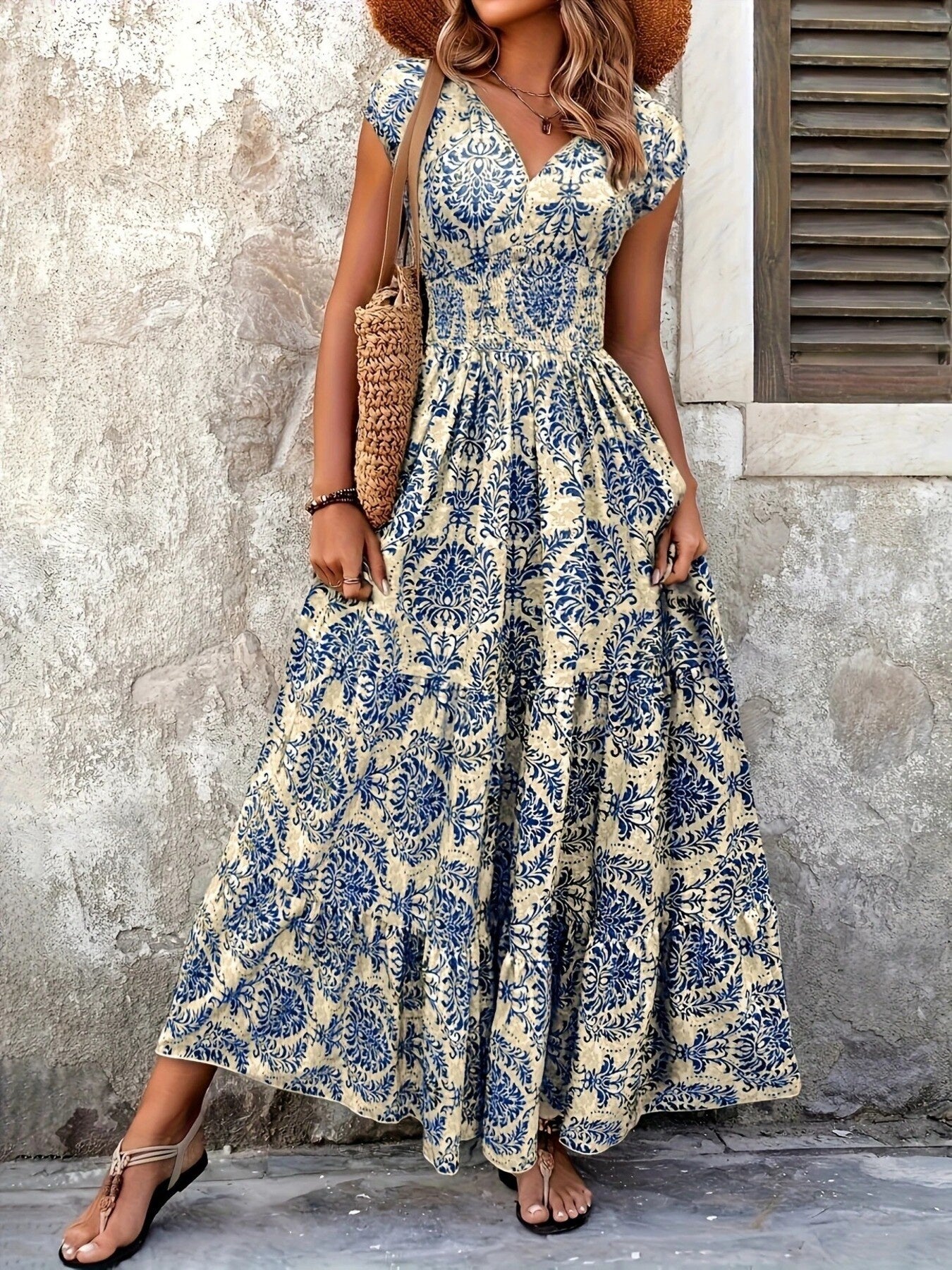 Woman wearing a floral dress standing against a textured wall.