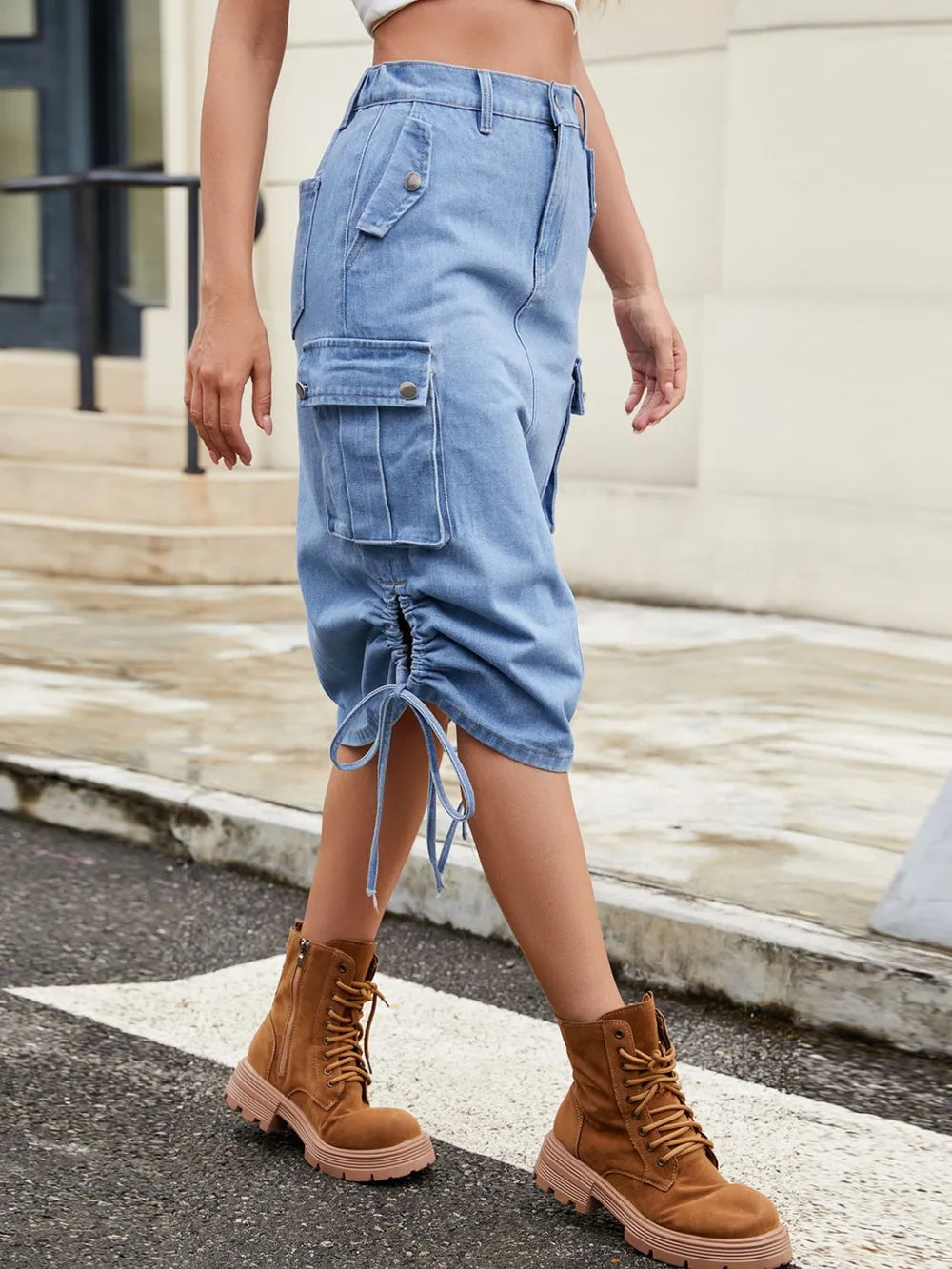 Person wearing blue cargo shorts and brown boots on a street.