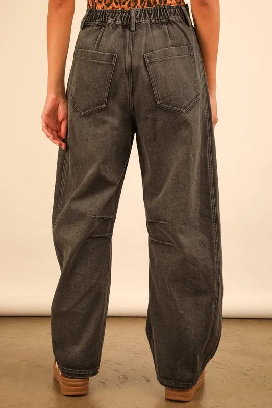 Person wearing dark gray wide-leg pants on a plain background