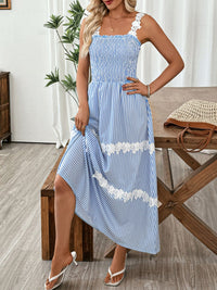 Woman wearing a blue and white striped dress with floral details in a home setting.
