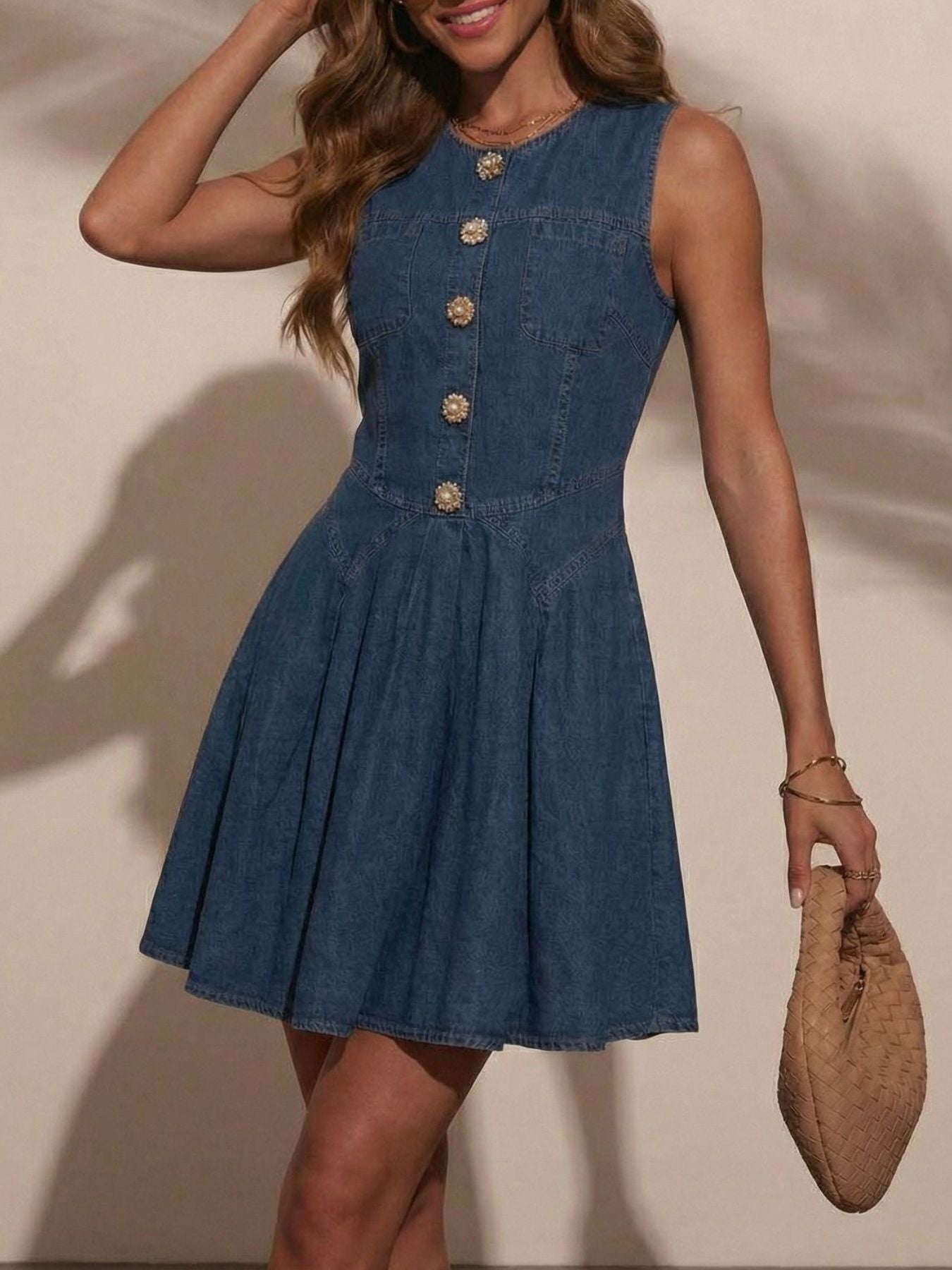 Woman wearing a blue denim dress with gold buttons against a neutral background