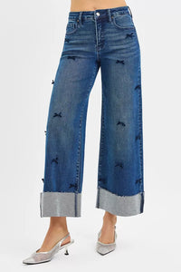 Wide-leg blue jeans with embroidered details on a white background