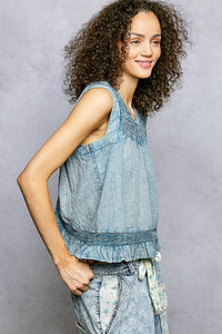 Woman wearing a sleeveless denim top with a gray background