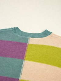 Color-blocked sweater with teal, purple, green, and beige sections on a light background