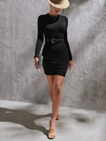 Woman wearing a black dress with a belt against a gray wall.